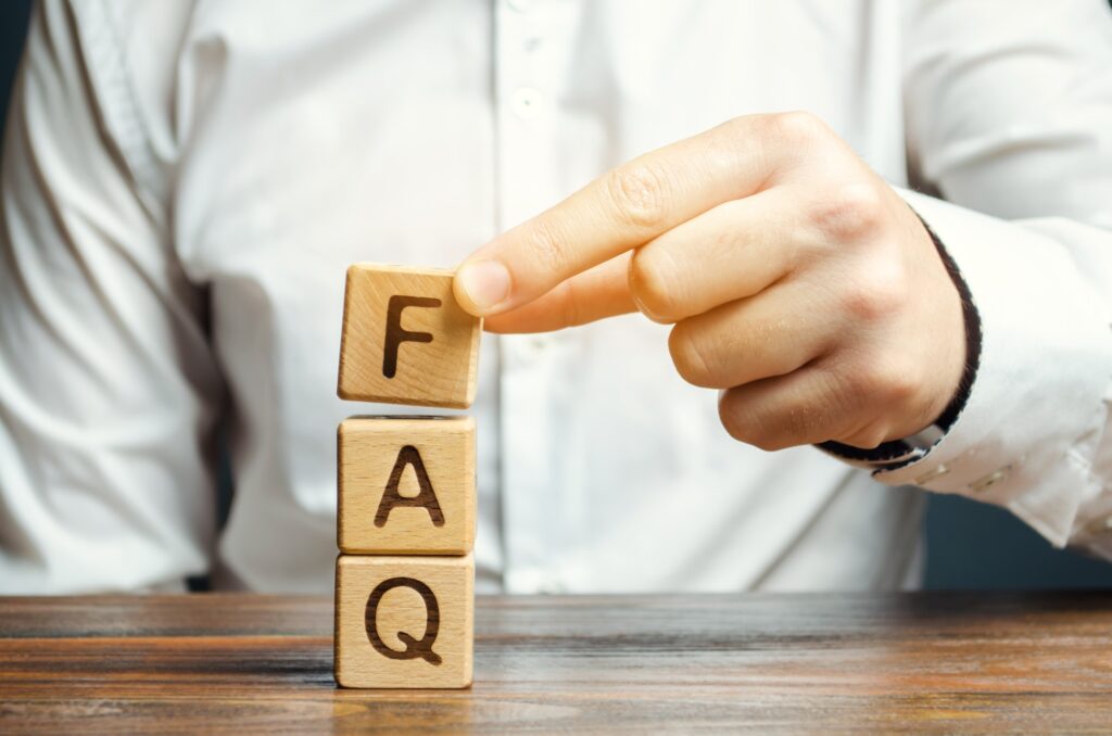 Businessman puts wooden blocks with the word FAQ (frequently asked questions)